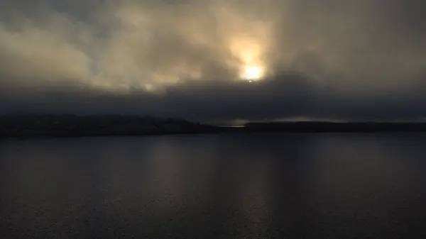 Rutland su gölü gölünün kışın gün batımında havadan görünüşü. Yoğun sis bulutları güneşi engelliyor ama kışın çok güzel renkler sağlıyor. Buzlu koşullar.