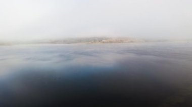 Kışın Rutland Su rezervuarı gölü üzerindeki sisli ve sisli gökyüzü manzarası İngiltere 'nin sisli katmanlarında kristal berrak su ve güneş ışığı kırıyor.
