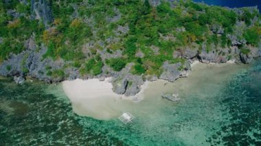 Filipinler 'deki Calauit Ulusal Parkı Coron Adası etrafındaki küçük adaların ve plajların 4k görüntüsü. Kristal berrak turkuaz mavi sular, palmiye ağaçları beyaz kumlu plajlar ve görünür mercan resifleri.. 