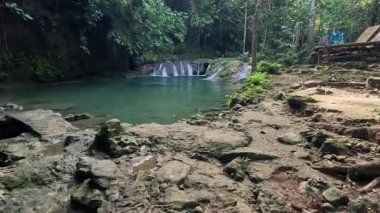 Point of view of huge tropical waterfall and lagoon, clear blue waters and verdant lush green jungle foliage in the Philippines Asia 