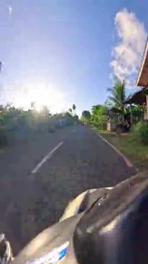 Point of view driving riding a motorbike scooter along tropical roads in the Philippines, Asia. lush green jungle and bright sunshine, travel content, scenic tourism, vacation holiday 