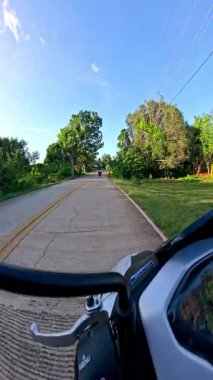 Point of view driving riding a motorbike scooter along tropical roads in the Philippines, Asia. lush green jungle and bright sunshine, travel content, scenic tourism, vacation holiday 