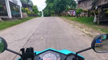 Point of view driving riding a motorbike scooter along tropical roads in the Philippines, Asia. lush green jungle and bright sunshine, travel content, scenic tourism, vacation holiday 
