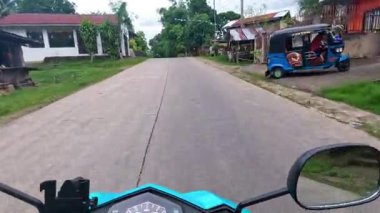 Point of view driving riding a motorbike scooter along tropical roads in the Philippines, Asia. lush green jungle and bright sunshine, travel content, scenic tourism, vacation holiday 