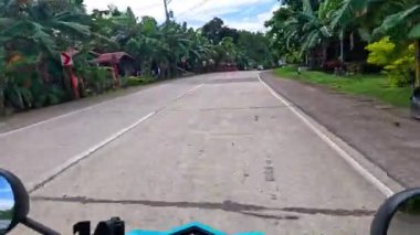 Point of view driving riding a motorbike scooter along tropical roads in the Philippines, Asia. lush green jungle and bright sunshine, travel content, scenic tourism, vacation holiday 