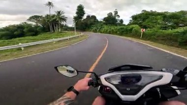 Point of view driving riding a motorbike scooter along tropical roads in the Philippines, Asia. lush green jungle and bright sunshine, travel content, scenic tourism, vacation holiday 
