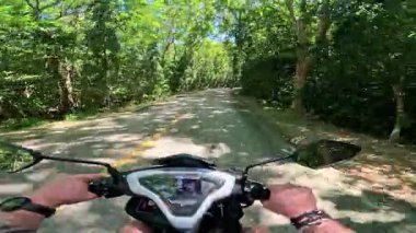 Point of view driving riding a motorbike scooter along tropical roads in the Philippines, Asia. lush green jungle and bright sunshine, travel content, scenic tourism, vacation holiday 
