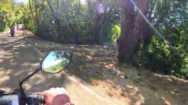 Point of view driving riding a motorbike scooter along tropical roads in the Philippines, Asia. lush green jungle and bright sunshine, travel content, scenic tourism, vacation holiday 