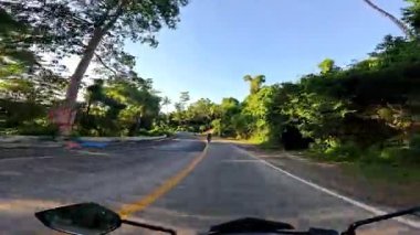 Point of view driving riding a motorbike scooter along tropical roads in the Philippines, Asia. lush green jungle and bright sunshine, travel content, scenic tourism, vacation holiday 