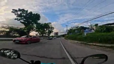 Point of view driving riding a motorbike scooter along tropical roads in the Philippines, Asia. lush green jungle and bright sunshine, travel content, scenic tourism, vacation holiday 