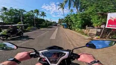 POV aerial drone view of motorbike riding along tropical roads, dense jungle greenery, sunlight, holiday travel and tourism adventure in Philippines
