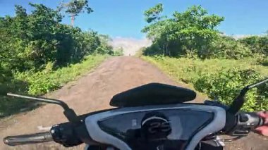 POV aerial drone view of motorbike riding along tropical roads, dense jungle greenery, sunlight, holiday travel and tourism adventure in Philippines