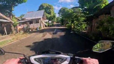 POV aerial drone view of motorbike riding along tropical roads, dense jungle greenery, sunlight, holiday travel and tourism adventure in Philippines