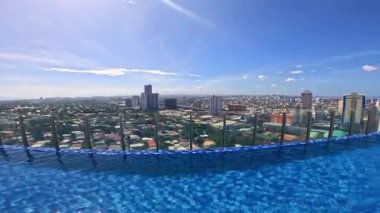 Point of view from top of hotel roof top pool in Manila, Philippines, Asia, holiday and vacation travelling, blue skies and blue pool water