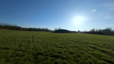 FPV aerial drone view close flying over rural farmland fields and livestock in England cold sunny Spring day, grass pastures 