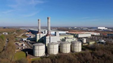 Aerial drone view of power plant, station with chimney stacks, gas burning chamber, fuel storage silos and industrial buildings, Corby England UK