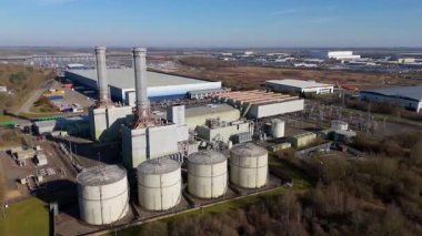 Aerial drone view of power plant, station with chimney stacks, gas burning chamber, fuel storage silos and industrial buildings, Corby England UK