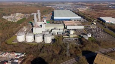 Aerial drone view of power plant, station with chimney stacks, gas burning chamber, fuel storage silos and industrial buildings, Corby England UK