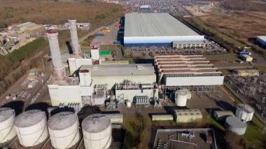 Aerial drone view of power plant, station with chimney stacks, gas burning chamber, fuel storage silos and industrial buildings, Corby England UK
