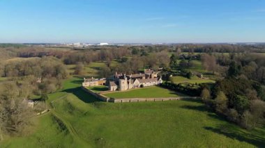 Ancient Rockingham Castle fortress seen from drone above, historic citadel and ramparts overlooking rural fields in bright spring weather, UK heritage site.
