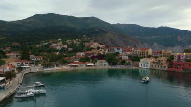 Asos balıkçı kasabasının hava aracı görüntüsü, gün batımında turistik bir yer. Yatlar ve deniz kenarındaki küçük evler, dağlık bölge, Kefalonia, Yunanistan ve Avrupa 'daki berrak mavi sular tatil beldesi turizmi
