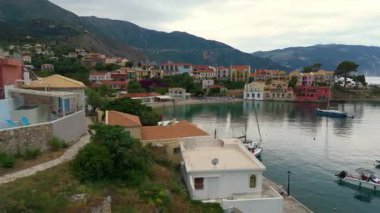 Asos balıkçı kasabasının hava aracı görüntüsü, gün batımında turistik bir yer. Yatlar ve deniz kenarındaki küçük evler, dağlık bölge, Kefalonia, Yunanistan ve Avrupa 'daki berrak mavi sular tatil beldesi turizmi