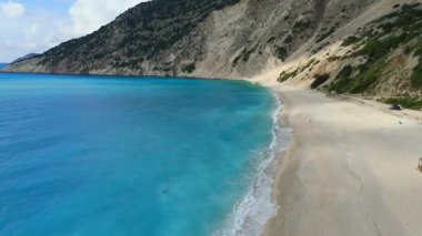 High footage of Myrtos beach and Ionian sea Kefalonia: vibrant blue water, white pebble arc, dramatic mountain cliffs