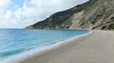 High footage of Myrtos beach and Ionian sea Kefalonia: vibrant blue water, white pebble arc, dramatic mountain cliffs