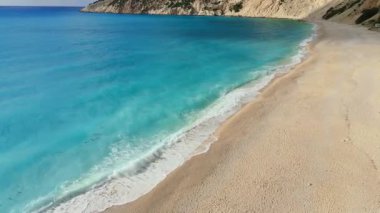 High footage of Myrtos beach and Ionian sea Kefalonia: vibrant blue water, white pebble arc, dramatic mountain cliffs