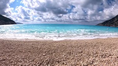 High footage of Myrtos beach and Ionian sea Kefalonia: vibrant blue water, white pebble arc, dramatic mountain cliffs