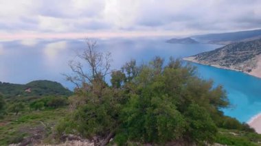 High footage of Myrtos beach and Ionian sea Kefalonia: vibrant blue water, white pebble arc, dramatic mountain cliffs