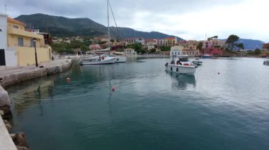 Asos balıkçı kasabasının hava aracı görüntüsü, gün batımında turistik bir yer. Yatlar ve deniz kenarındaki küçük evler, dağlık bölge, Kefalonia, Yunanistan ve Avrupa 'daki berrak mavi sular tatil beldesi turizmi