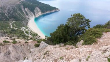 High footage of Myrtos beach and Ionian sea Kefalonia: vibrant blue water, white pebble arc, dramatic mountain cliffs