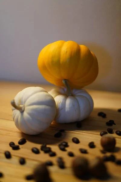pumpkins, coffee beans, and hazelnuts spread out on wood table