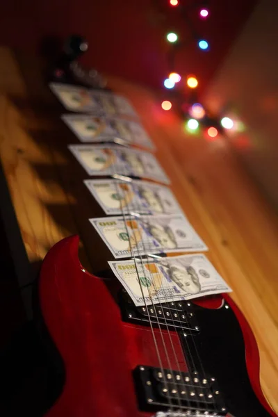 one hundred dollar bills on top of a red guitar, money on guitar, guitar money, red guitar, money spread, wealth, financial freedom, music money