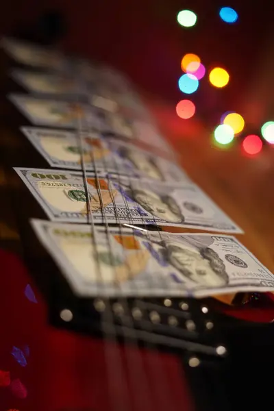 one hundred dollar bills on top of a red guitar, money on guitar, guitar money, red guitar, money spread, wealth, financial freedom, music money