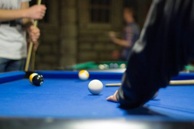 Bilardo oyunu devam ediyor, oyuncu ıstakayla topa vurmayı hedefliyor