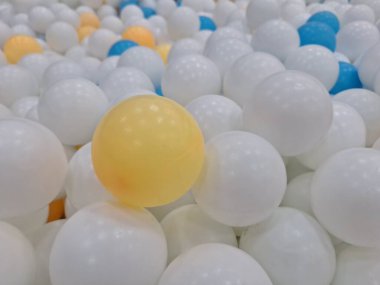 Üst üste yığılmış birçok plastik topun görüntüsü, renkli beyaz, turuncu, mavi.