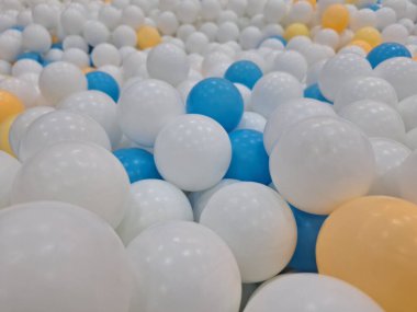 Üst üste yığılmış birçok plastik topun görüntüsü, renkli beyaz, turuncu, mavi.