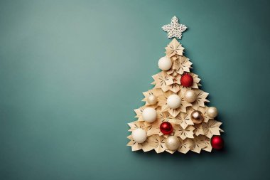 Handcraft composition of origami colored balls and a Christmas tree cut out of beige cardboard with copy space. Flat lay clipart