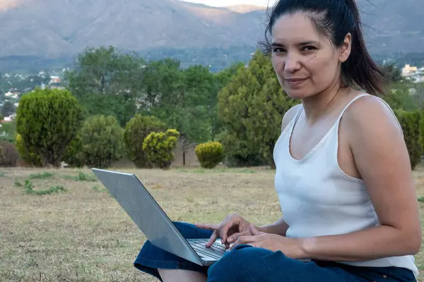 Latin kız, arka planda dağları görebileceğiniz güzel bir parka gitti. Yanında not defteri ve cep telefonu vardı..