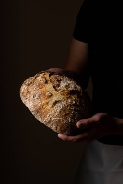 Beyaz ekşi ekmek ile poz veren çekici, genç, beyaz bir Kafkas şefi. Ekşi mayalı ekmek sahnenin ana kahramanıdır. Koyu arkaplanda güzel altın tonlarla öne çıkar..