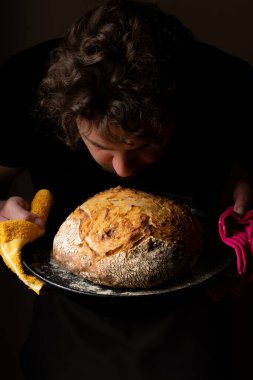 Beyaz ekşi ekmek ile poz veren çekici, genç, beyaz bir Kafkas şefi. Ekşi mayalı ekmek sahnenin ana kahramanıdır. Koyu arkaplanda güzel altın tonlarla öne çıkar..