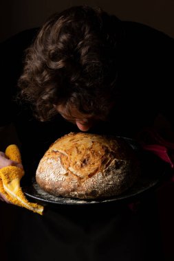 Beyaz ekşi ekmek ile poz veren çekici, genç, beyaz bir Kafkas şefi. Ekşi mayalı ekmek sahnenin ana kahramanıdır. Koyu arkaplanda güzel altın tonlarla öne çıkar..