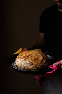 Beyaz ekşi ekmek ile poz veren çekici, genç, beyaz bir Kafkas şefi. Ekşi mayalı ekmek sahnenin ana kahramanıdır. Koyu arkaplanda güzel altın tonlarla öne çıkar..