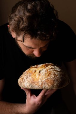 Beyaz ekşi ekmek ile poz veren çekici, genç, beyaz bir Kafkas şefi. Ekşi mayalı ekmek sahnenin ana kahramanıdır. Koyu arkaplanda güzel altın tonlarla öne çıkar..