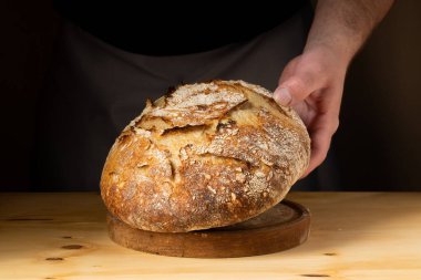 Ekmek somonlu ekmeği tutan genç bir adamın elleri. Ekmeği koyu arka planda güzel altın tonlarla renklendiriyor..