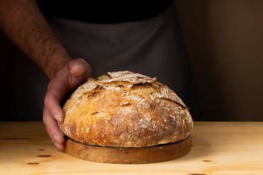 Ekmek somonlu ekmeği tutan genç bir adamın elleri. Ekmeği koyu arka planda güzel altın tonlarla renklendiriyor..