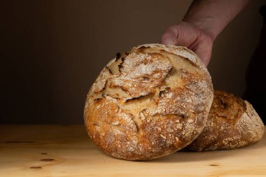 Ekmek somonlu ekmeği tutan genç bir adamın elleri. Ekmeği koyu arka planda güzel altın tonlarla renklendiriyor..