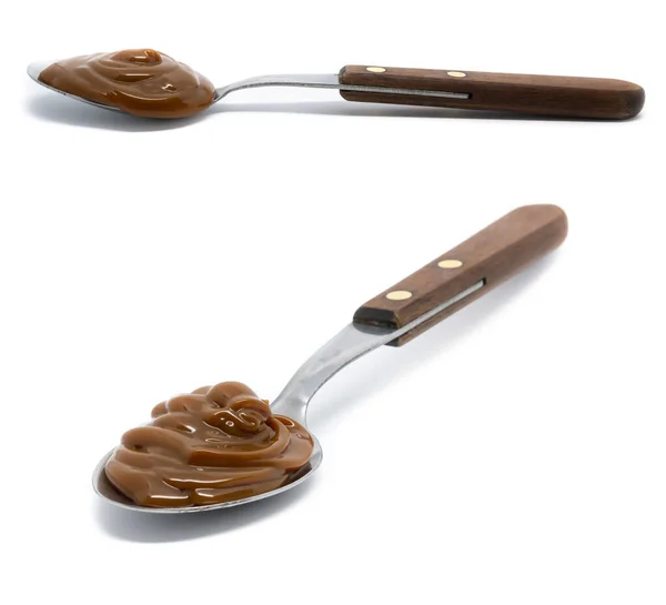 Dulce de leche, izole edilmiş arka planda bir kaşık odun ve metal..